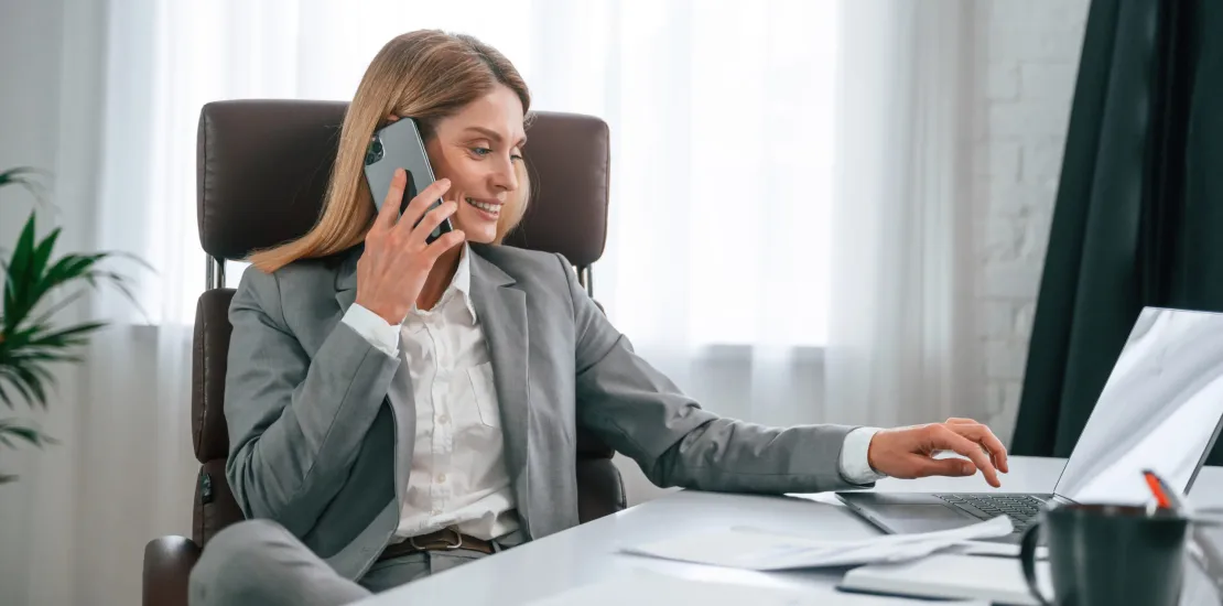 Talking by phone. Woman in business formal clothes is working in office.