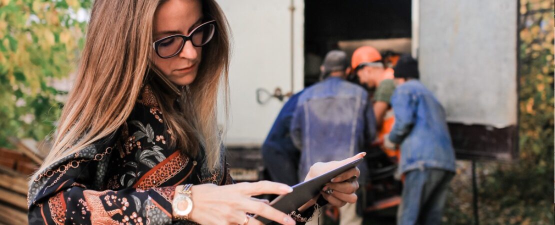 blog-mobiles-arbeiten Mobiles Arbeiten - Frau steht mit Tablet vor Umzugswagen und telefoniert nebenbei.