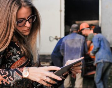 Mobiles Arbeiten - Frau steht mit Tablet vor Umzugswagen und telefoniert nebenbei.