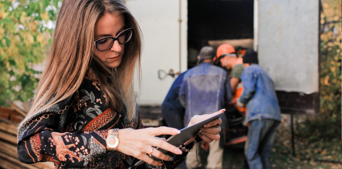 Mobiles Arbeiten - Frau steht mit Tablet vor Umzugswagen und telefoniert nebenbei.